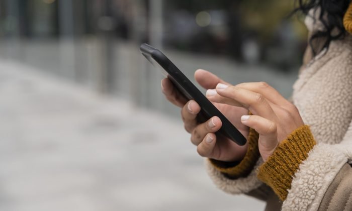 mulher-usando-seu-smartphone-lado-de-fora-com-espaco-de-copia