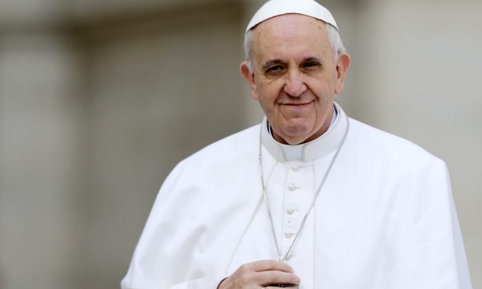 El papa Francisco toca su crucifijo mientras lo conducen a través de la multitud durante su audiencia general inaugural, en la Plaza de San Pedro, en el Vaticano, el miércoles 27 de marzo de 2013. Francisco pidió el miércoles que se ponga fin a la violencia y los saqueos relacionados con el golpe de estado del fin de semana en la República Centroafricana, en su primera apelación de ese tipo por la paz desde que se convirtió en papa. (AP foto/Andrew Medichini)