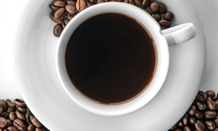 Cup of coffee and coffee beans, flat lay on a white background.