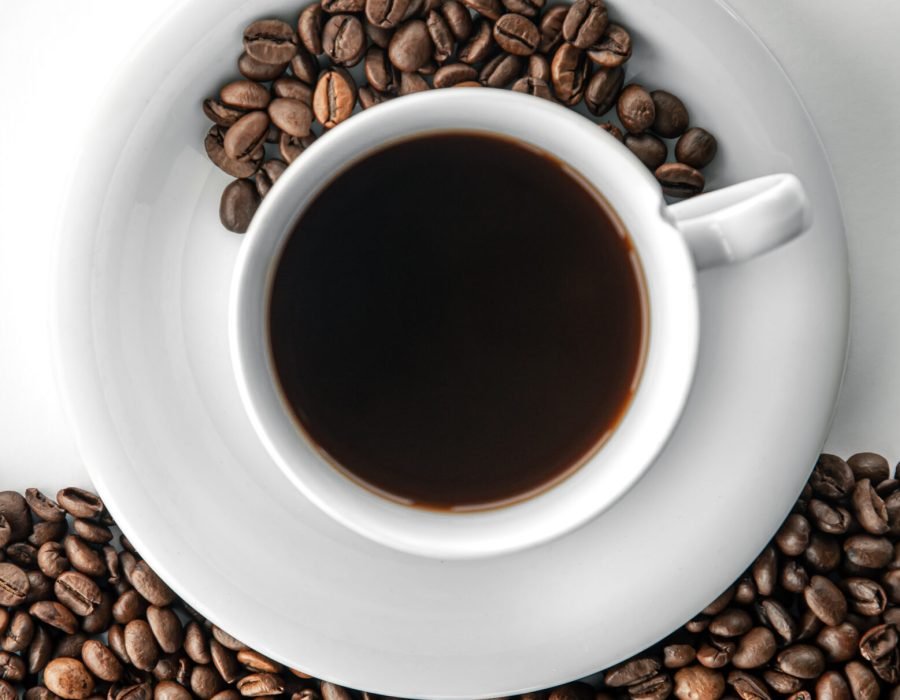 Cup of coffee and coffee beans, flat lay on a white background.